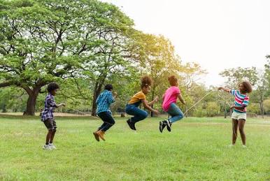 Children jumping rope together in a sunny park—Statesboro Community Center